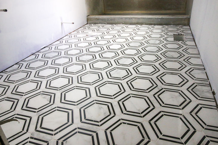 The Builder Depot Carrara Venato Hexagon Nero Strip Marble Mosaic Tile installed on bathroom floor