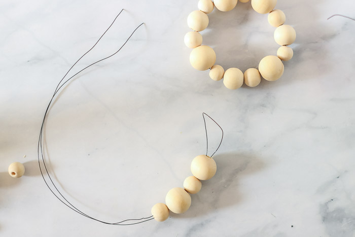 stringing wooden beads onto looped wire